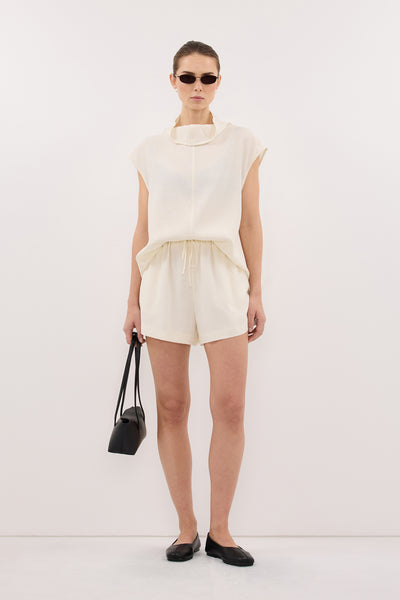 Stas wearing CALIA CREAM FUNNEL NECK TOP